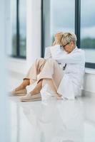 A Tired Female Doctor Looking Worried During Quick Break In An Empty Hospital Hallway photo