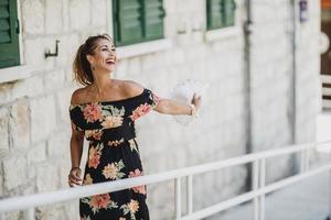 mujer alegre con vestido de flores divirtiéndose mientras camina en el día de verano foto