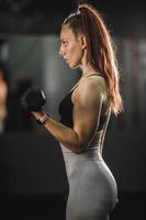 mujer musculosa entrenando con pesas en el gimnasio foto