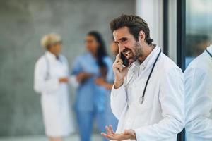 A Stressed Doctor Talking On A Smartphone In A Hospital Hallway photo