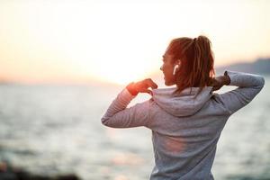 Woman Enjoying Summer Sunset And Relaxing During Training Near The Sea photo