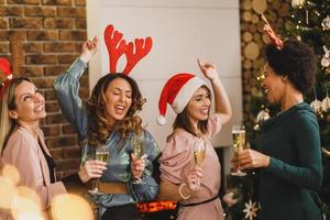cuatro amigas multiétnicas divirtiéndose y bailando en casa fiesta de navidad