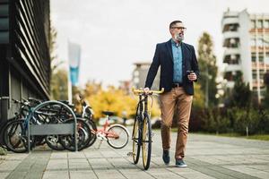 A Businessman Drinking Coffee During Go To Work With A Bike photo