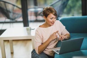 mujer que asiste a una reunión en línea en una computadora portátil mientras trabaja desde casa foto