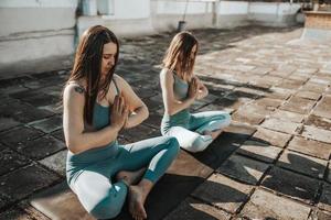 Two Woman Doing Yoga Outdoors On A Rooftop Terrace photo