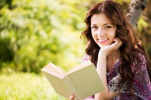 retrato de niña con un libro en el parque foto