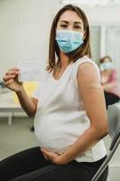 Pregnant Woman Holding Covid-19 Vaccination Record Card photo