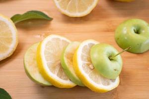 rodaja de manzana y limón con hoja sobre fondo de madera foto