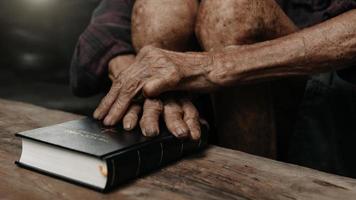 Oldmans hands together in prayer to God along with the bible In the Christian concept and religion, woman pray in the Bible photo