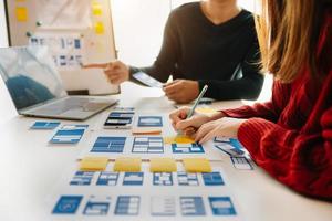 UX developer and ui designer brainstorming about mobile app interface wireframe design with customer breif and color code at modern office. photo
