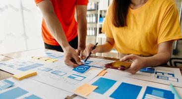 UX developer and ui designer brainstorming about mobile app interface wireframe design with customer breif and color code at modern office. photo