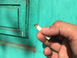 mano sosteniendo un cigarrillo que está a punto de agotarse foto