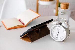 alarm clock, tablet and notepad on a white table. Workplace in the office. Businessman items photo