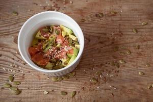 Poke de aguacate, arroz y salmón con calabaza, semillas de sésamo sobre un fondo de madera. espacio de copia de comida asiática foto