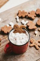 ginger man in a cup of cocoa with a big red bow on a wooden background, top view. Various Christmas sweets with a cup of cocoa on the table. Christmas flatlay photo
