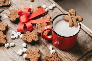 ginger man in a cup of cocoa with a big red bow on a wooden background, top view. Various Christmas sweets with a cup of cocoa on the table. Christmas flatlay photo
