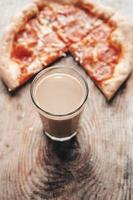 coffee drink in a transparent glass with pizza on a wooden background. Cocoa and pizza, top view. photo