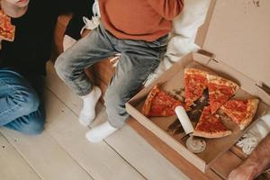 snack on pepperoni pizza, out of the box on the floor, top view. Pizza box and round knife with pizza slices in the box. Food delivery home photo