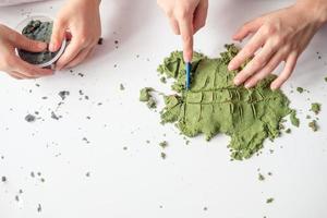 children play with Kinetic sand at home. Development of fine motor skills, top view photo