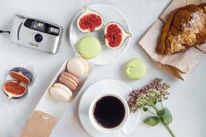 aesthetic film camera flatlay, cups of coffee, figs and macarons on a white background, top view photo