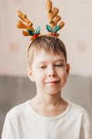 portrait of a boy in reindeer Christmas antlers Preparing for the Christmas party. New Years masquerade of children photo
