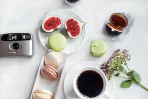 aesthetic film camera flatlay, cups of coffee, figs and macarons on a white background, top view photo