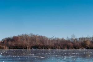 A frozen lake, the circles on the ice. In the background a coniferous forest photo