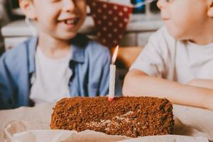 rollo dulce con relleno de chocolate y velas navideñas y niños felices en un fondo neutro. concepto de cumpleaños. pastel de rollo con una vela, primer plano. foto