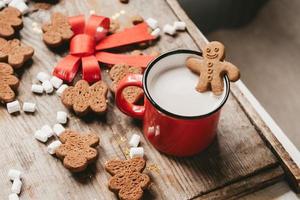 ginger man in a cup of cocoa with a big red bow on a wooden background, top view. Various Christmas sweets with a cup of cocoa on the table. Christmas flatlay photo