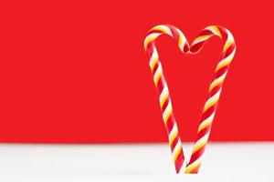 Christmas candy canes on a red background. Heart on a red background. Heart made of lollipops. Heart for valentine's day photo