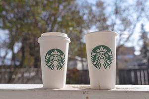 Marinette,WI,USA - Nov10, 2022- Cups of Starbucks Hot Coffee put on white snow in winter garden, fresh and hot beverage take away concept.Starbucks Cafe Coffee Shop. photo