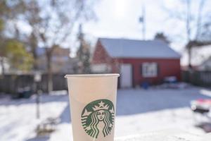 Marinette,WI,USA - Nov14, 2019- Cups of Starbucks Hot Coffee put on white snow in winter garden, fresh and hot beverage take away concept.Starbucks Cafe Coffee Shop. photo