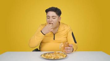 Eating unhealthy foods. Orange background. Boy eating hamburger with french fries.