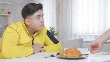 il sovrappeso bambino fa non volere per mangiare. il bambino chi vuole per mantenere il suo peso sotto controllo fa non volere per mangiare il pasta quello arriva nel davanti di lui mentre studiando. video