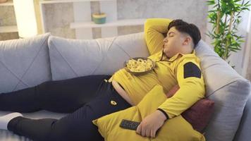 Excess weight. Obesity kid. Obese boy falling asleep while watching TV.