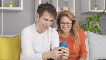 Young man looking at the phone with his mother. Young man showing something to his mother on the phone. video