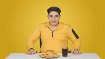 Obesity. Boy looking at hamburger and licking his lip. video