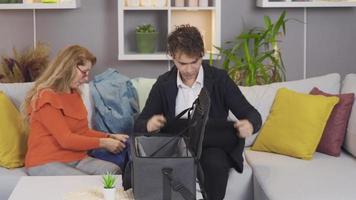 Mom is crying and son is packing suitcase. Mother and son are packing suitcases. video