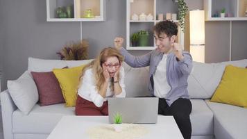 Joyful mother and son. Happy news. Young man looking at laptop with mature mother, giving happy news, rejoicing and hugging video