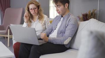 Young man showing something from laptop to his mother. Mother and son looking at laptop. video