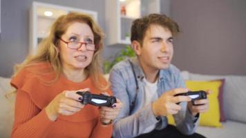 mère et fils jouant au jeu vidéo avec des consoles de jeux. jeune homme jouant à des jeux avec sa mère avec des consoles de jeux.