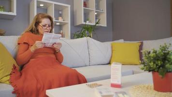 Sick mother looking at medicines with her son. The mother looking at the drug insert is busy and her son is helping out. video