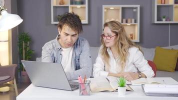 Mother helping her son with his study. Mother and son study with laptop and books at the table. video