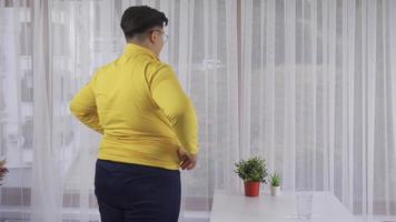 The person who is bothered by their weight. An overweight person looks out the window and is unhappy. video