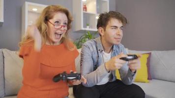 junger mann, der mit seiner mutter mit spielkonsolen spielt. mutter und sohn spielen videospiel mit spielkonsolen. video