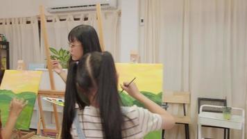 une enseignante asiatique enseigne et montre aux enfants sur la peinture acrylique couleur sur toile dans la classe d'art, apprenant de manière créative avec compétence à l'école primaire. video