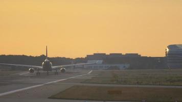 el avión aterriza en la pista iluminada temprano en la mañana al atardecer. video