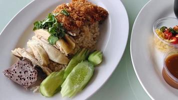 steamed rice topped with boiled chicken Mixed with Fried Chicken Served with broth and dipping sauce. The most popular street food in Thailand is called Khao Mun Gai. video