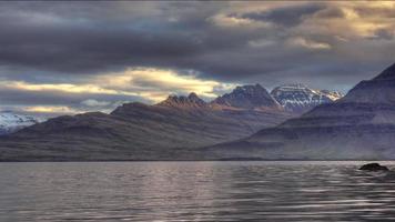 hd video van rimpelingen Aan een meer Bij zonsondergang middernacht zon over- een berg reeks en fjord in IJsland. hdr, hd video