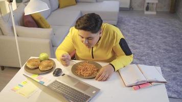 te zwaar tiener consumeren pasta. zwaarlijvig jongen eet pasta tussen klas. video